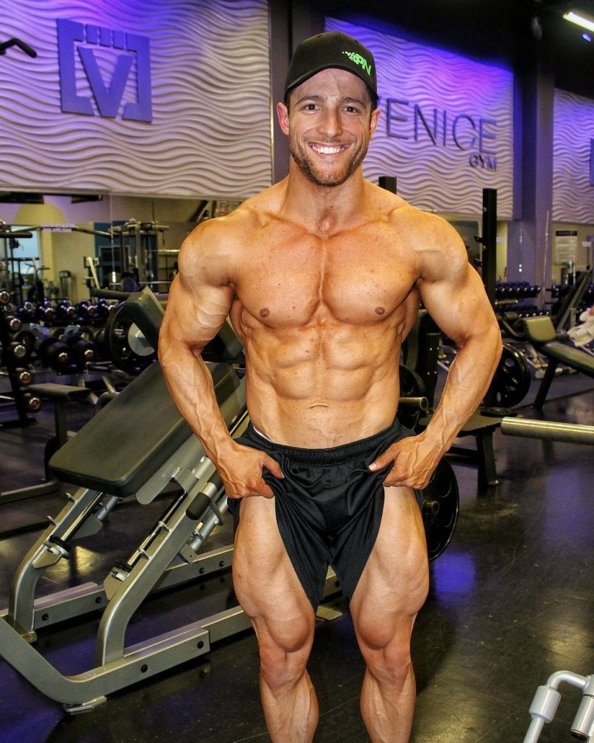 Jonathan Plante standing shirtless in a gym flexing his muscles