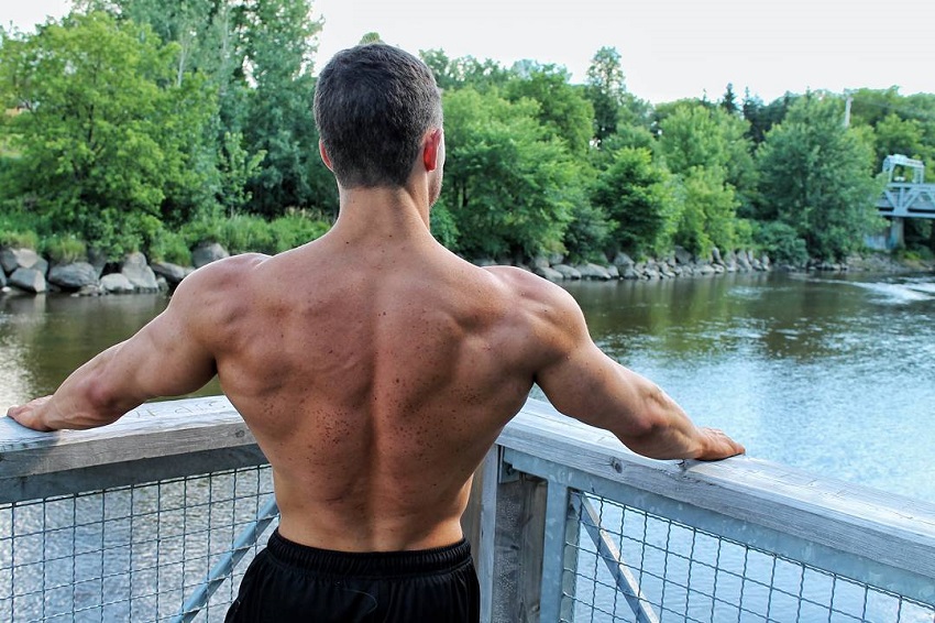 Jonathan Plante standing shirtless by a fence overlooking a river