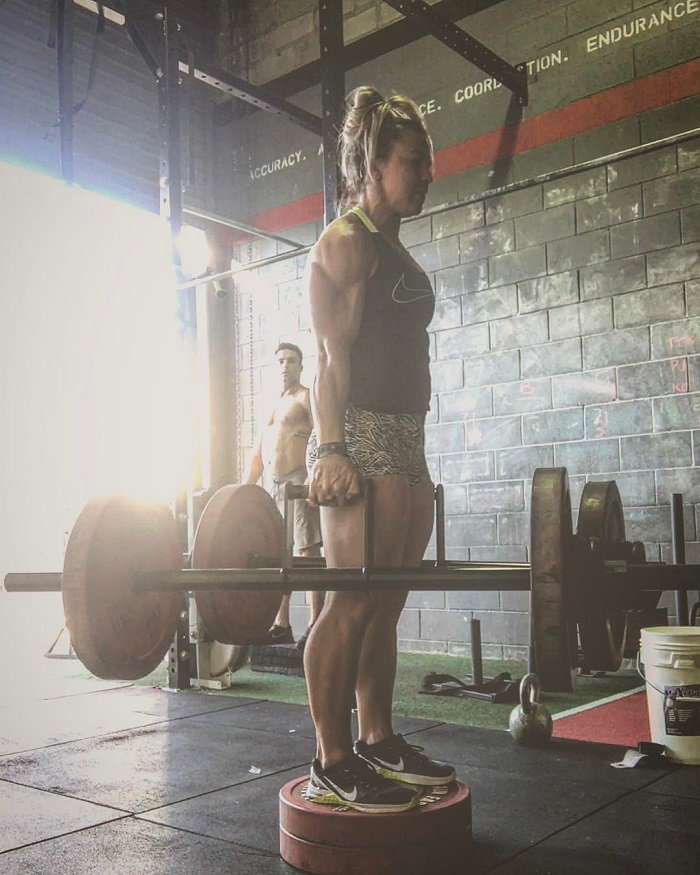 Kara Webb Saunders lifting heavy bars during a CrossFit training