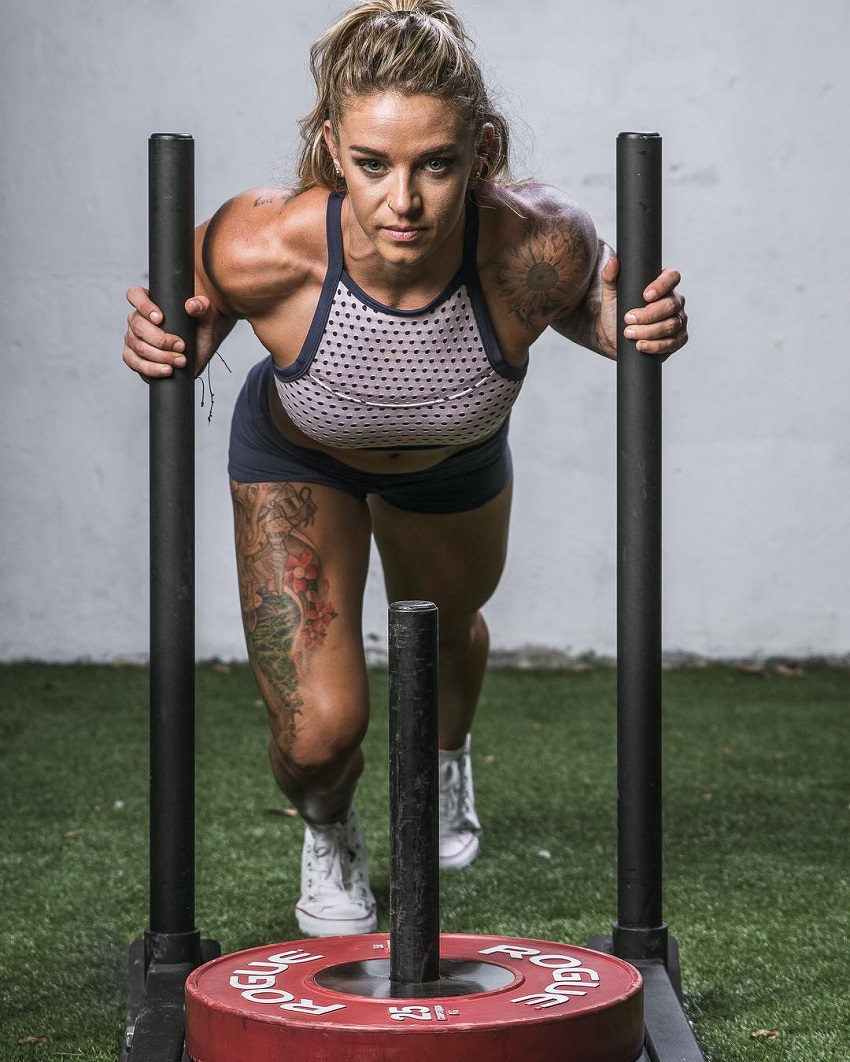 Lauren Herrera pushing a cart with weights on it looking strong and fit