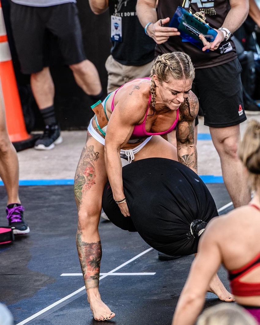 Lauren Herrera lifting a heavy sand bag during a CrossFit event