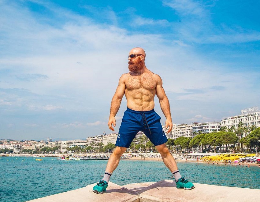 Lucas Parker standing shirtless by the sea,