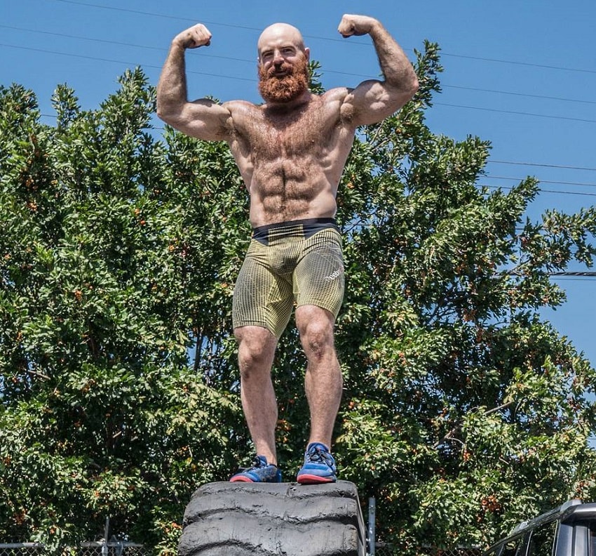 Lucas Parker standing on a big tire flexing his muscles
