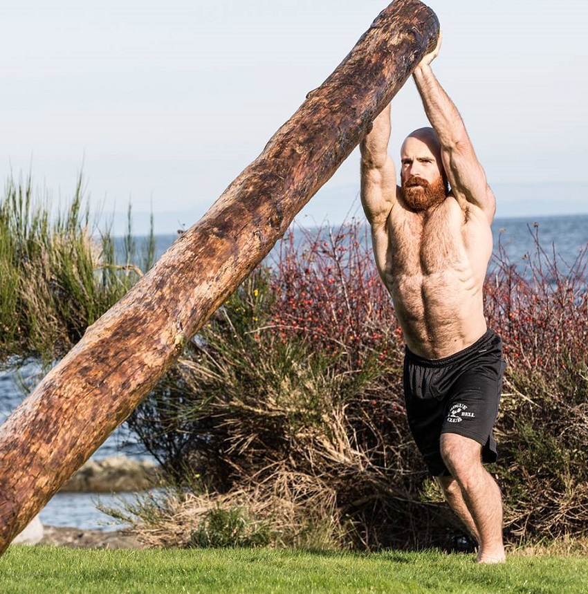 Lucas Parker lifting a heavy log while being shirtless