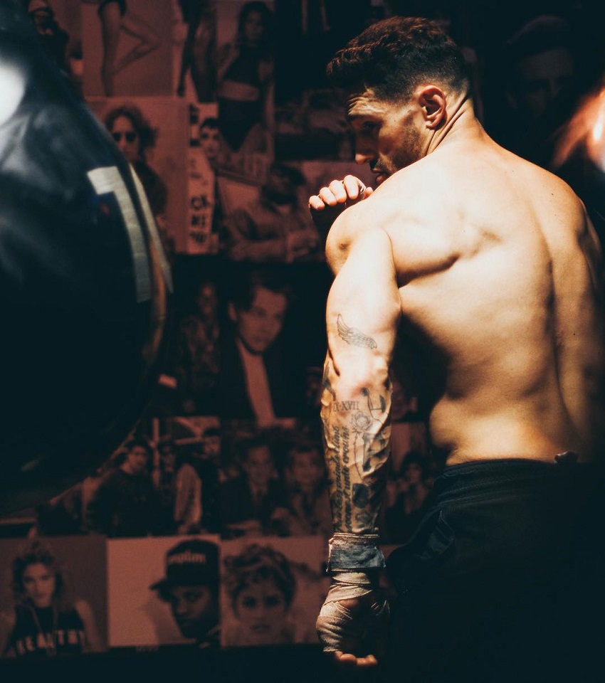 Noah Neiman practicing boxing on a punching bag while being shirtless