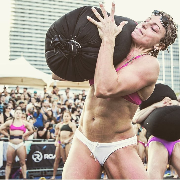 Tiffany Szemplinski carrying a heavy bag of sand during a CrossFit contest