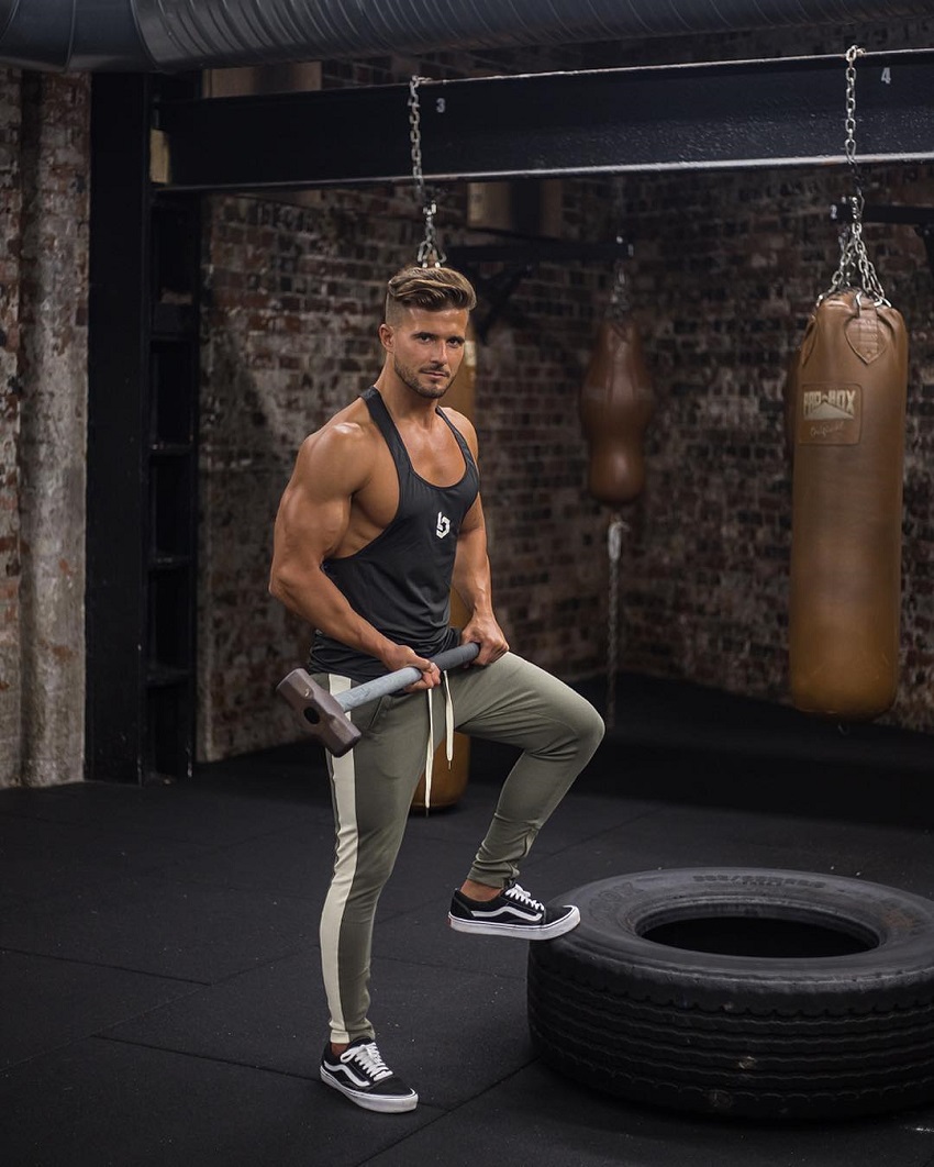 Antonio Pozo standing by a big tire with a sledgehammer in his hands