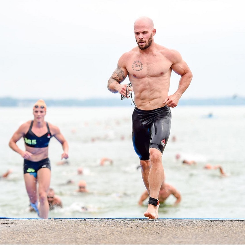 Chris Spealler running on the beach competing against other CrossFitters