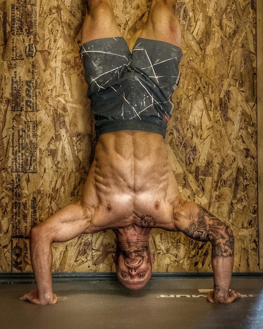 Chris Spealler doing a shirtless handstand looking ripped