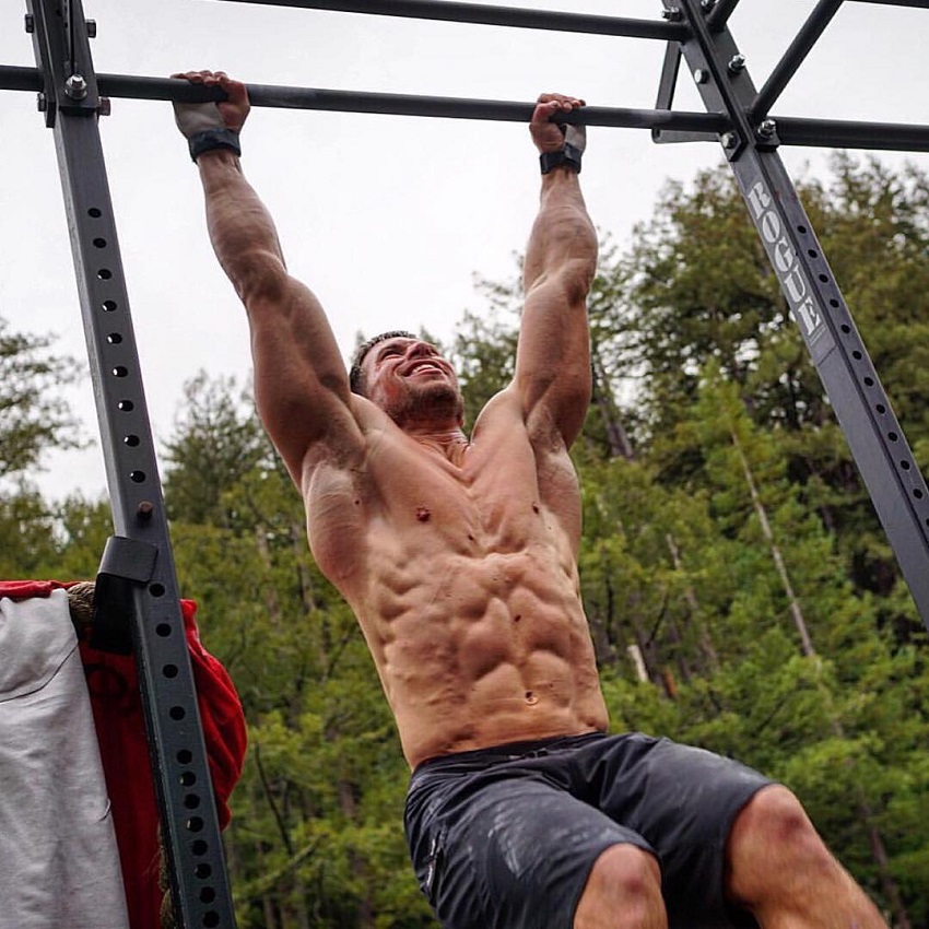 Dan Bailey performing pull ups shirtless, looking ripped