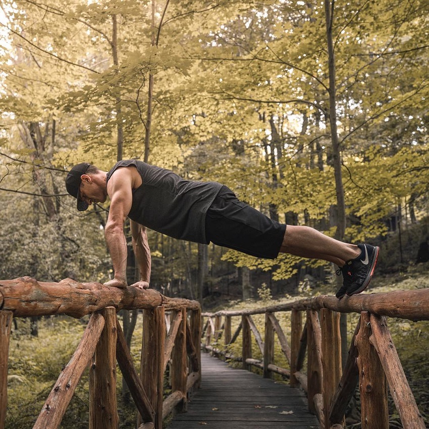 Don Saladino doing a push up on a wooden bridge looking fit