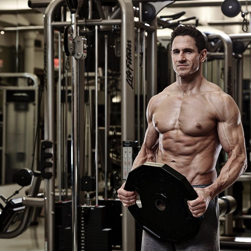 Don Saladino carrying a weight plate in the gym