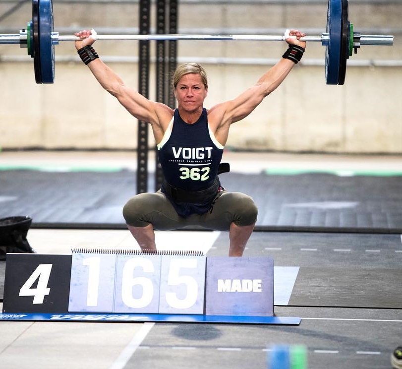 Rebecca Voigt Miller doing an overhead press with a barbell during a CrossFit contest