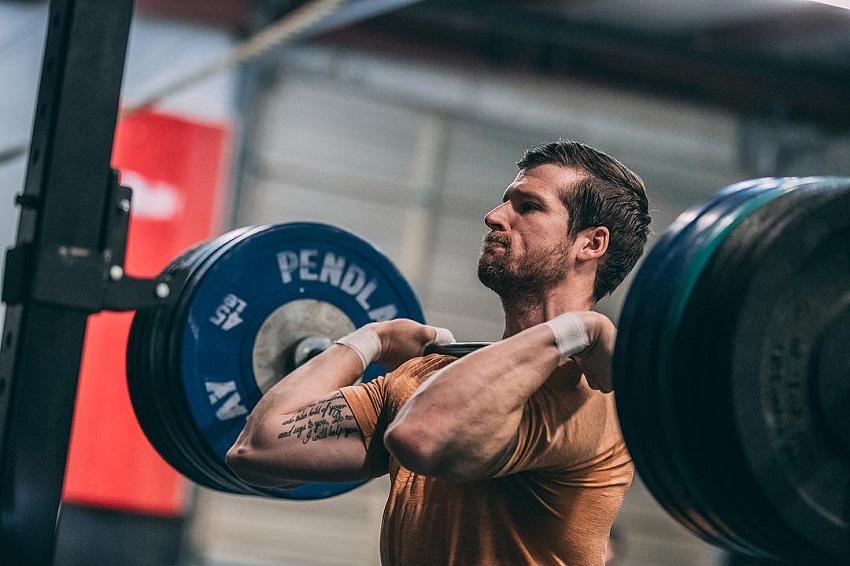 Travis Mayer lifting a barbell loaded with weights looking strong