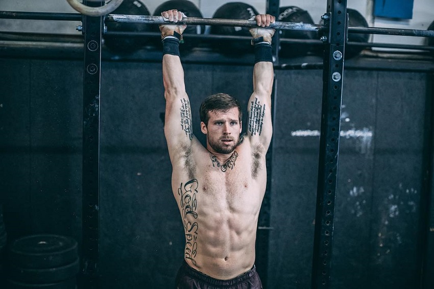 Travis Mayer hanging on a bar shirtless