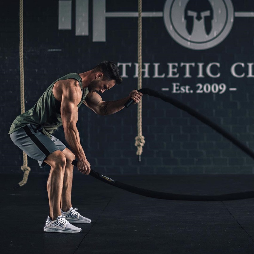 Daniel Fox performing battle ropes in the gym his arms looking strong and ripped