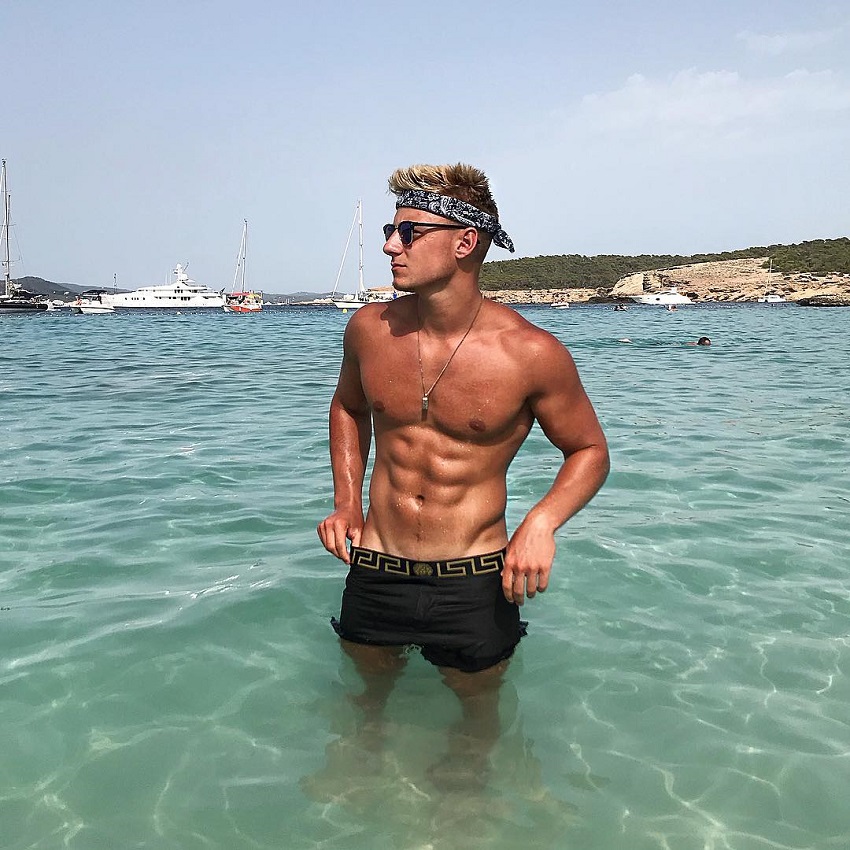 Max Wyatt standing shirtless in the sea looking strong and ripped