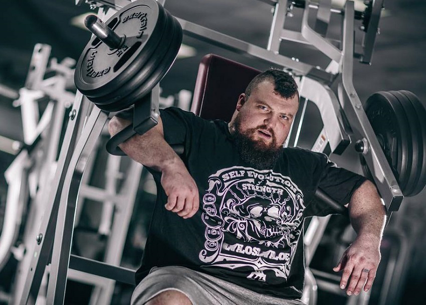 Eddie Hall resting on a chest machine looking big and strong