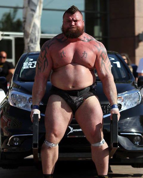 Eddie Hall lifting a car looking huge and strong