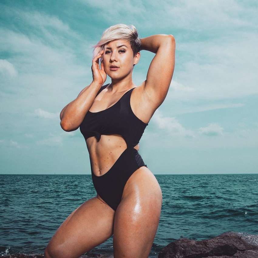 Elena Soboleva posing by the sea in her black swimsuit looking fit and toned