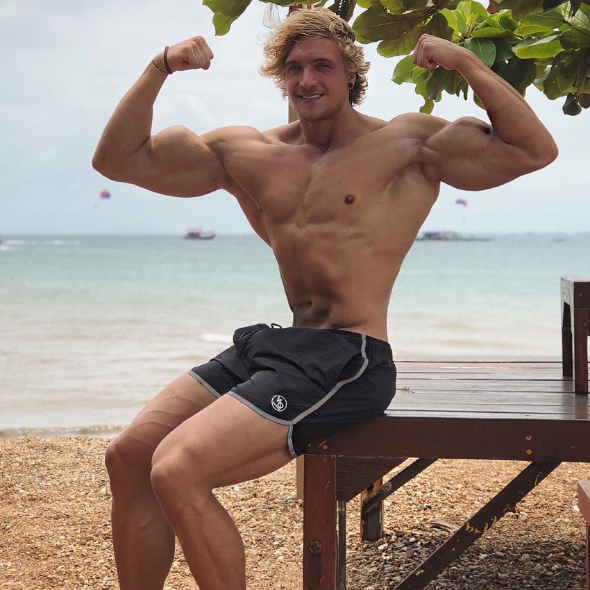 Jo Linder flexing his arms on the beach looking aesthetic and strong