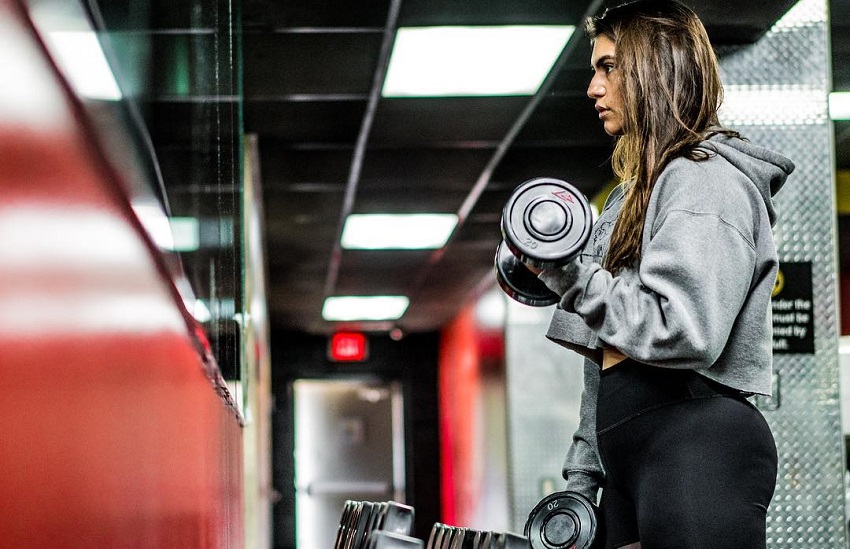 Laura Micetich doing biceps curls in her gym sweater