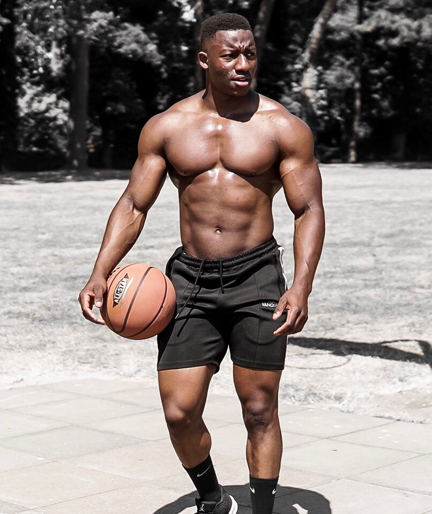 Lubomba Munkuli holding a basketball while shirtless, looking strong and ripped