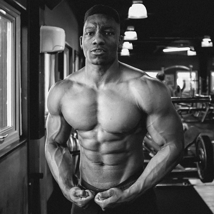 Lubomba Munkuli flexing shirtless in a black and white photo