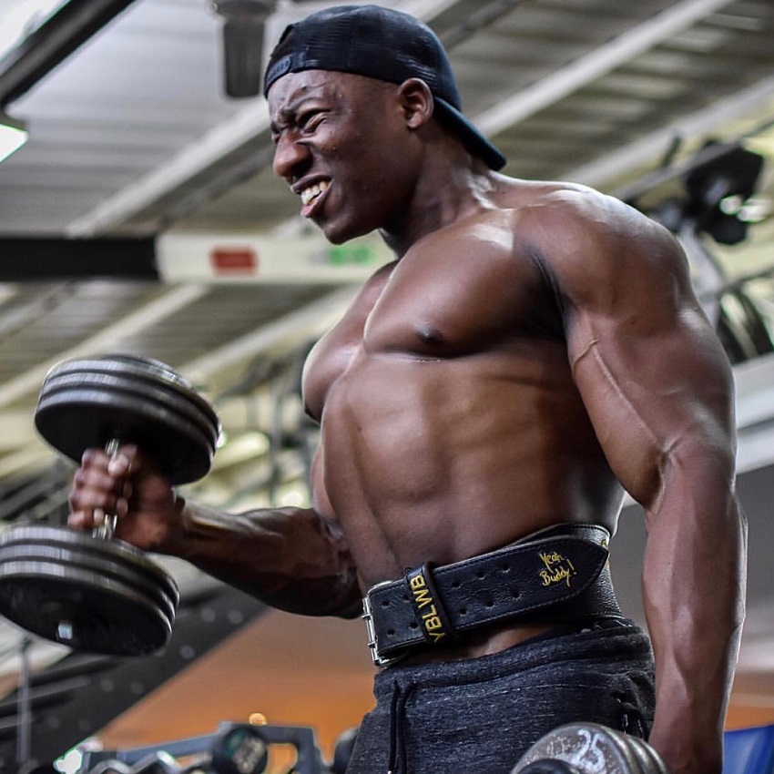 Lubomba Munkuli doing dumbbell biceps curls while shirtless