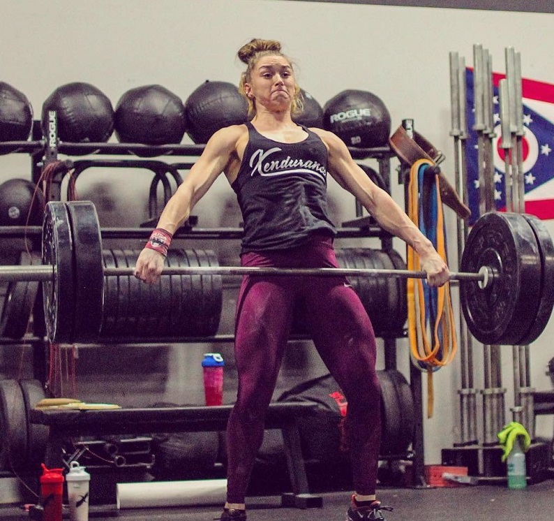 Mattie Rogers lifting an extremely heavy barbell loaded with weights during training