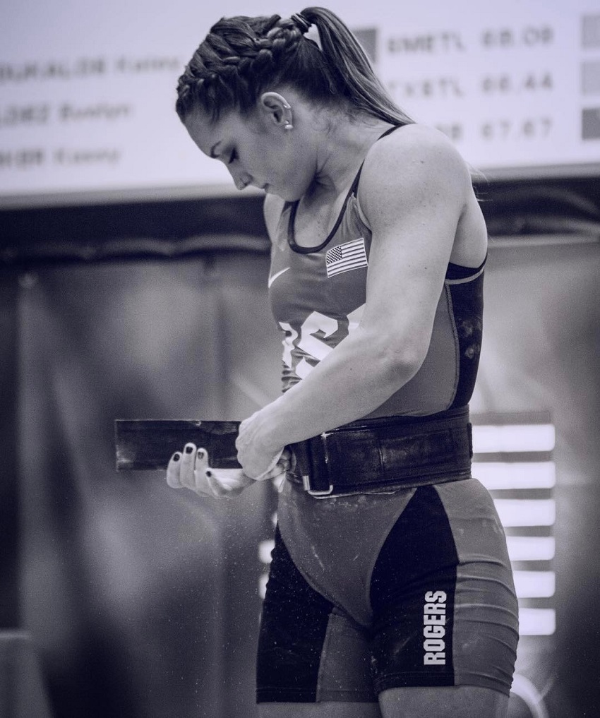Mattie Rogers putting a belt on during a weightlifting contest