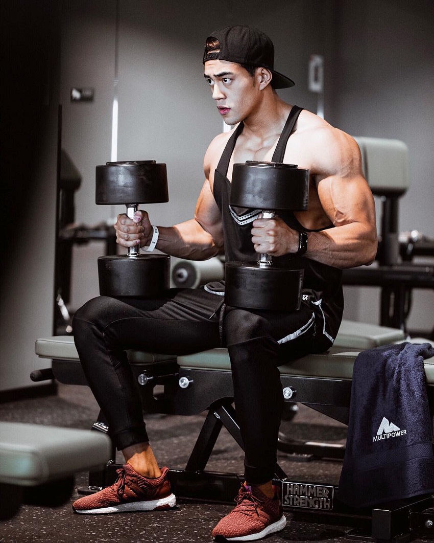 Nam Vo sitting with dumbbells looking strong and fit