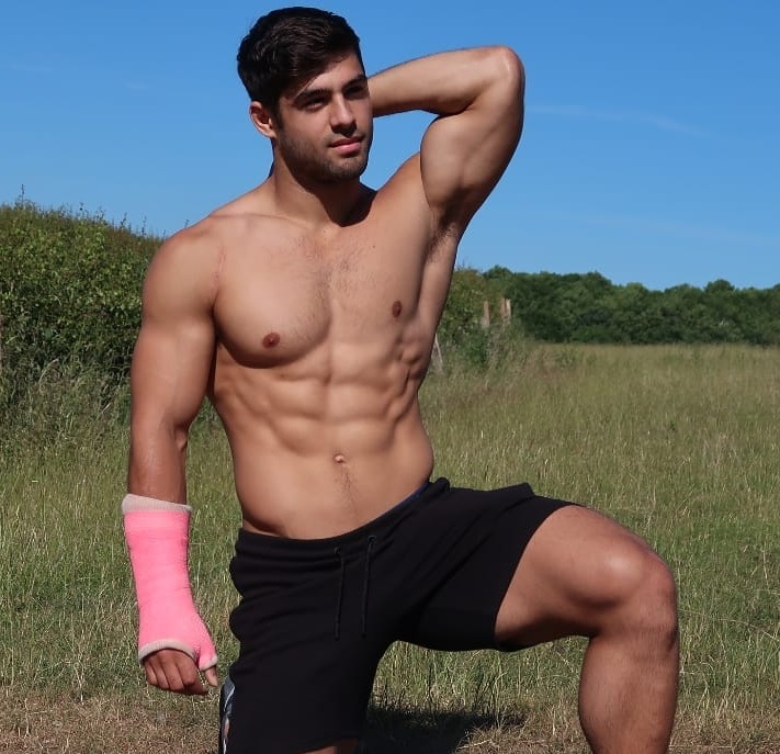 Dan Tai posing shirtless in a meadow