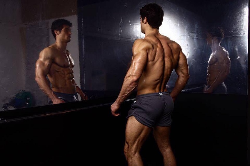 Josh Watson looking at himself in the mirror looking strong and lean