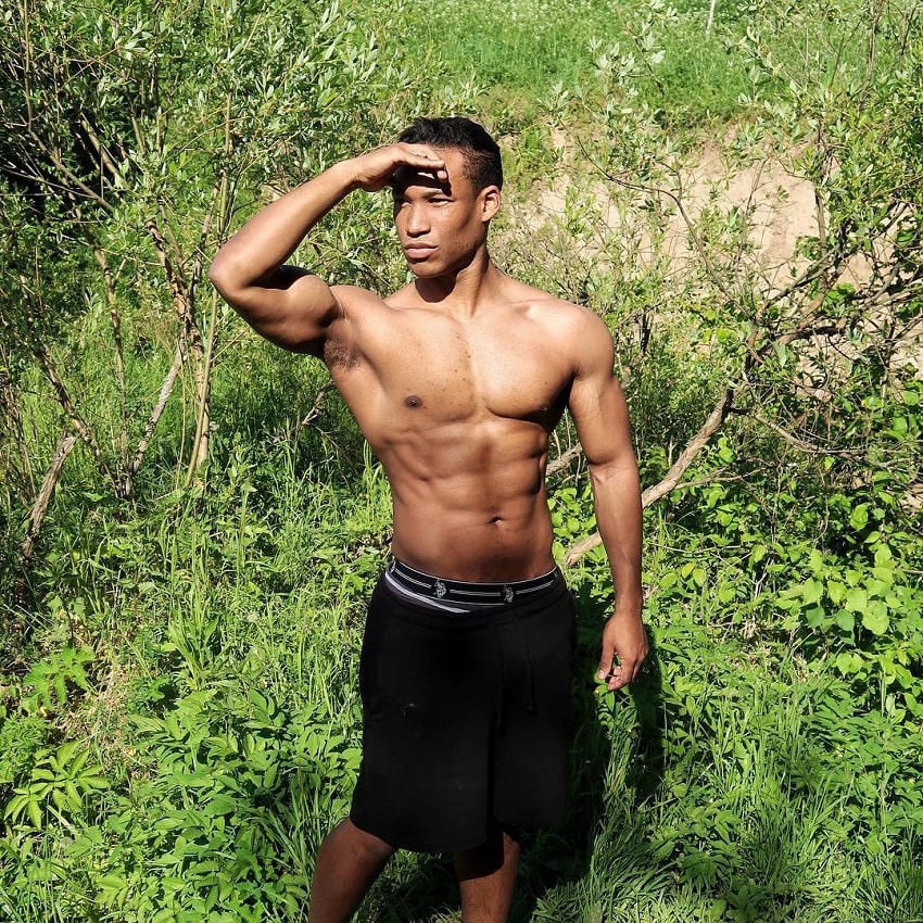 Mike Diamonds standing shirtless outdoors in nature looking in the distance
