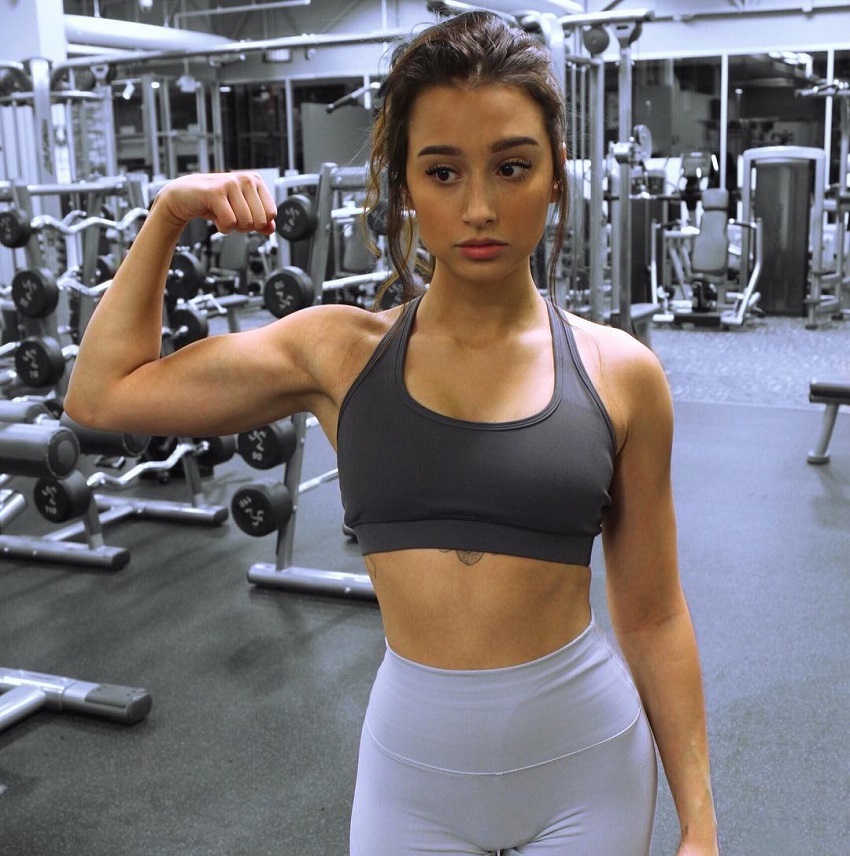 Amber Gianna flexing her biceps in the gym