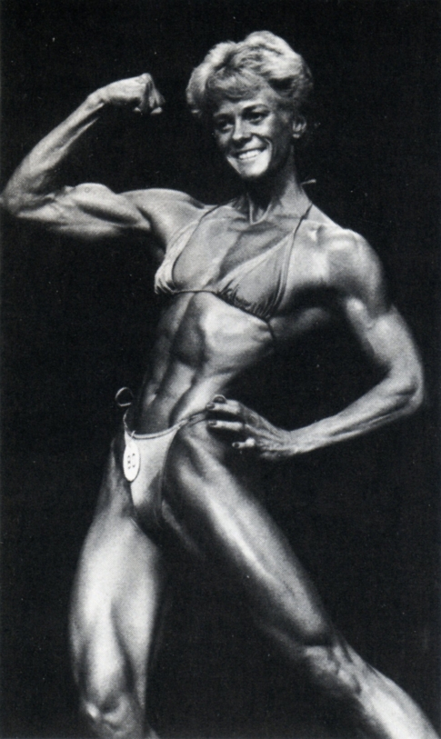 Ellen van Maris during her early bodybuilding days flexing her biceps on the stage