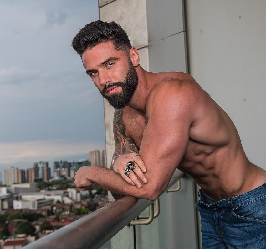 Fernando Lozada Zuniga leaning against a balcony of a huge building, looking fit and lean