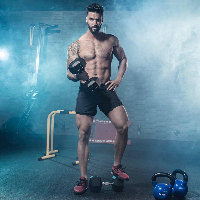 Fernando Lozada Zuniga posing shirtless with a dumbbell in a professional fitness photo shoot