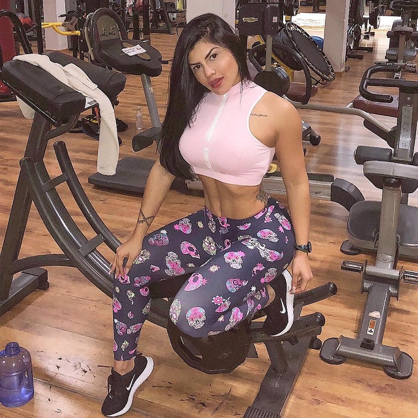 Karol Prado sitting on a cardio machine after a sweaty workout