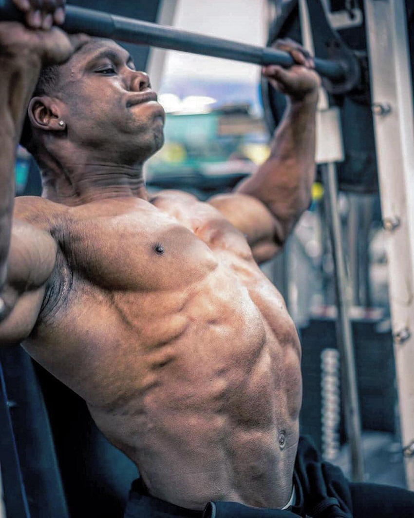 Keone Pearson doing a heavy overhead press while shirtless