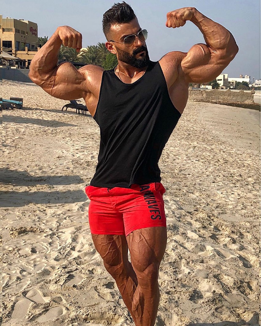 Mohamed El Qadi doing a front double biceps flex looking huge and ripped