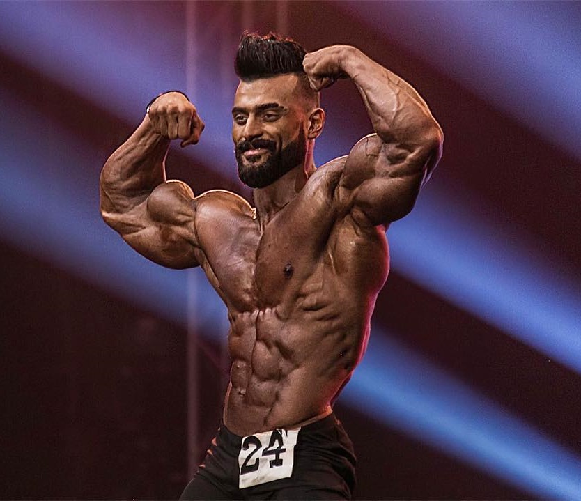 Mohamed El Qadi flexing on a bodybuilding stage