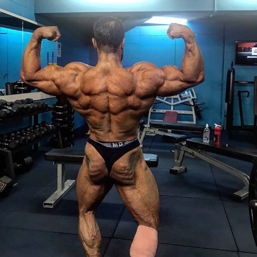 Rouollah Mirhoseini hitting a shirtless back double biceps pose