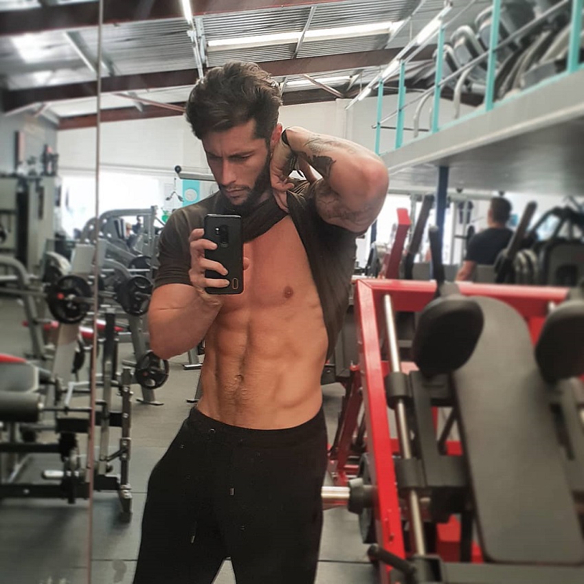 Vince Azzopardi flexing his abs in a gym selfie