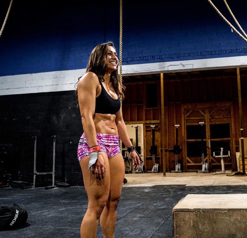 Cristina Bayardelle standing in a CrossFit gym, looking at someone and smiling