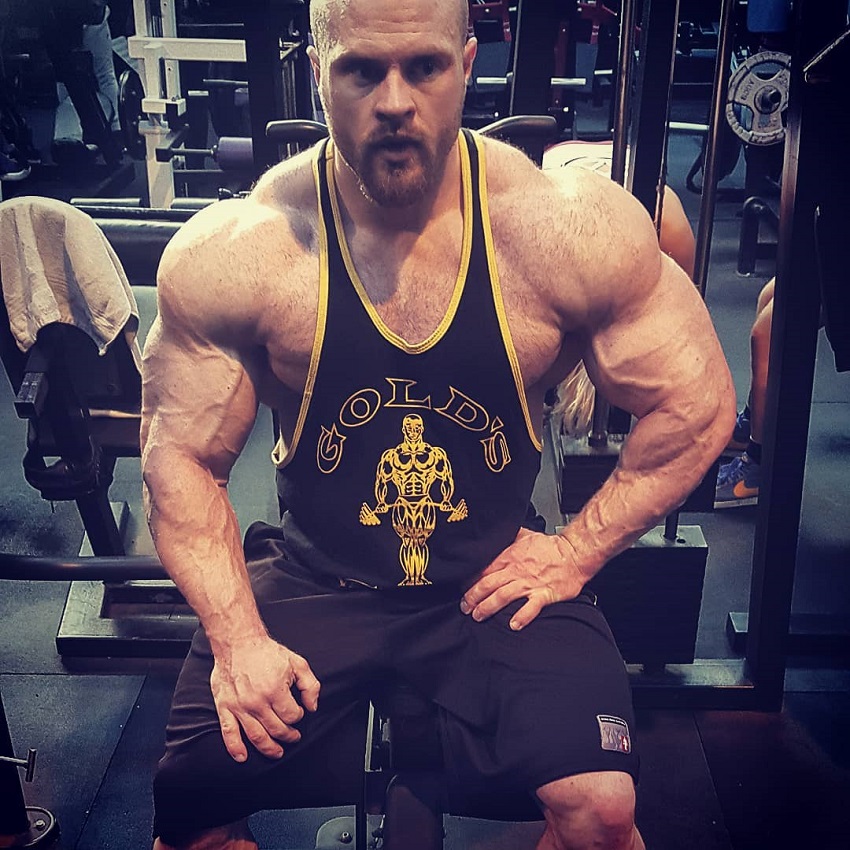 James Hollingshead sitting on a bench in the gym looking huge and ripped