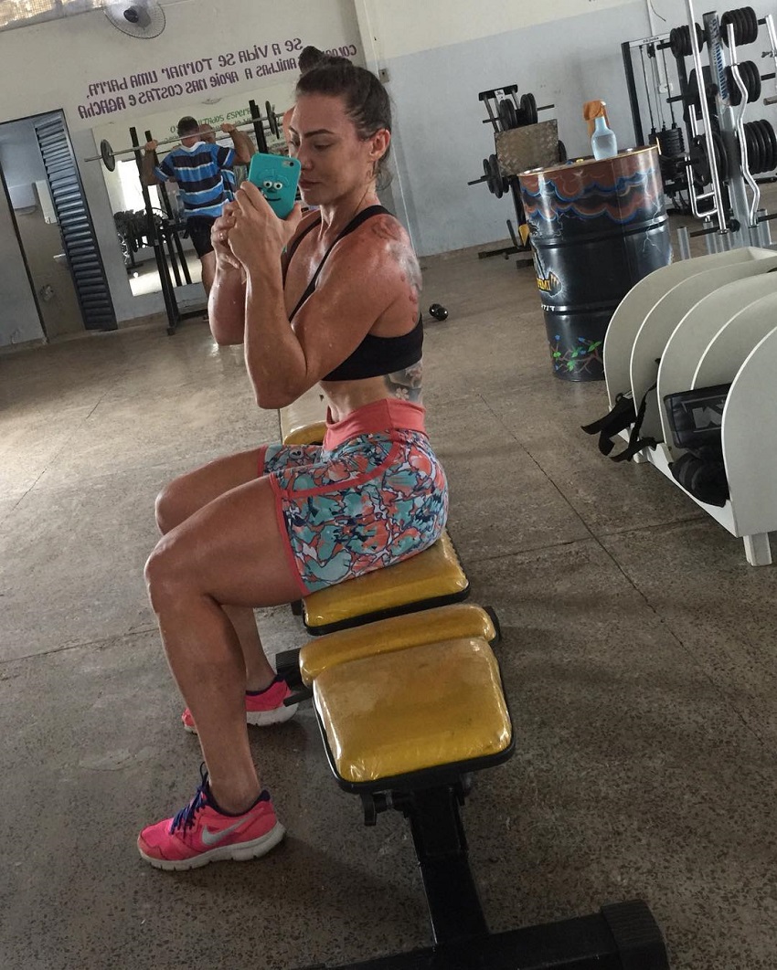 Kelly Karina showcasing her awesome legs while sitting on a bench in the gym