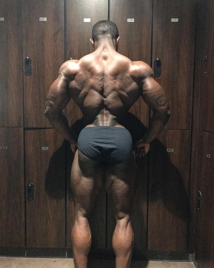 Kenneth Owens posing his ripped lats in downlighting