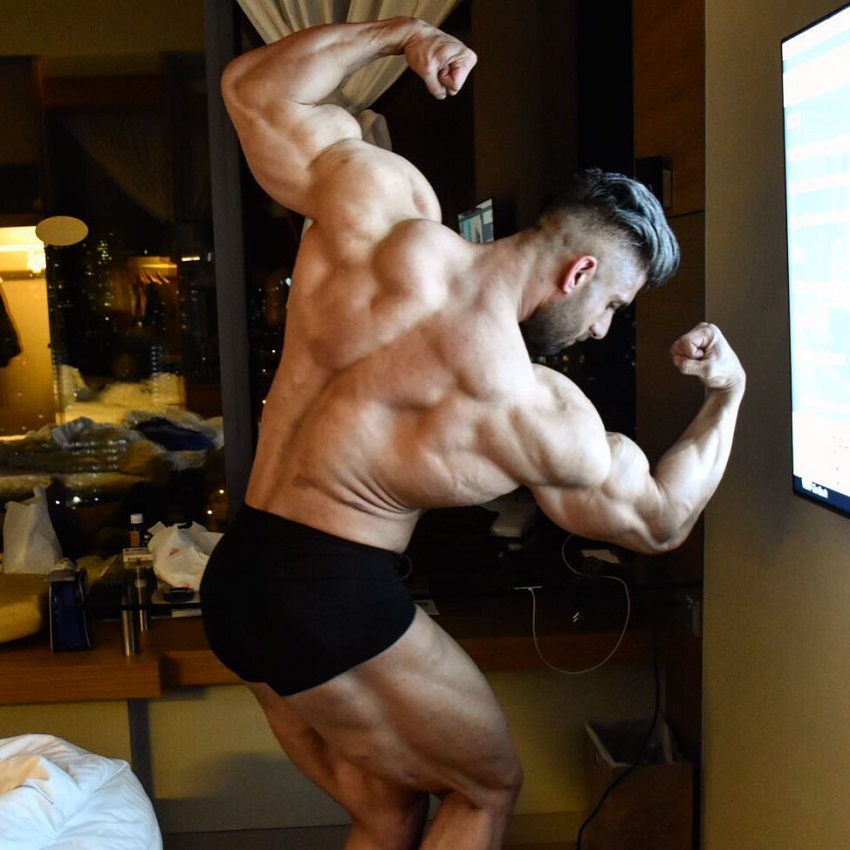 Ahmad Parvin flexing his back and biceps looking fit